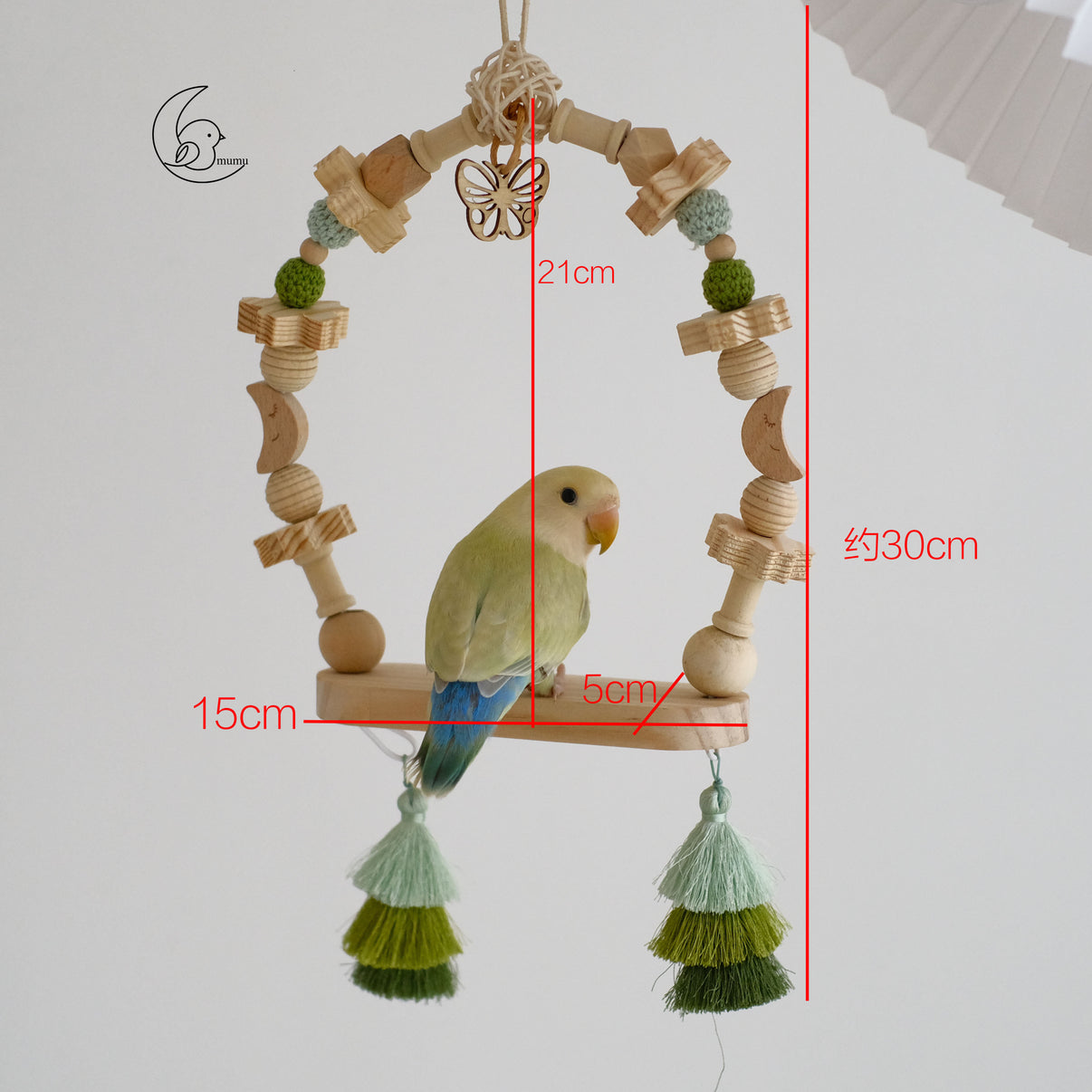 Bird hanging on wooden swing perch decorated with beads, tassels, and butterfly charm